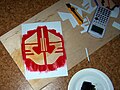 A painted stencil and the tools used to make it. Used on a T-shirt.