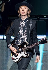 Musician Beck wearing a guitar.