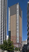 Ground-level view of a rectangular, window-dotted high-rise; the facades are tri-colored with white, beige and gray areas