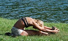 Photograph of a woman practising a seated yoga pose in a park