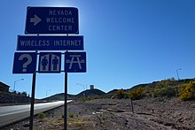 closeup of blue road signs pointing towards a Nevada welcome center with various roadside amenities in 2012