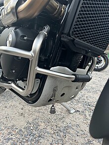 A 1-inch pewter bell hanging below a Triumph Motorcycle.