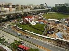 A bird eye view of the CCL construction site taken from above. Various construction equipment lay scattered in an excavated pit located beside the completed NEL entrance.