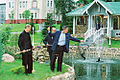 George Bush and Vladimir Putin fish from a fish pond, while an aide holds a landing net