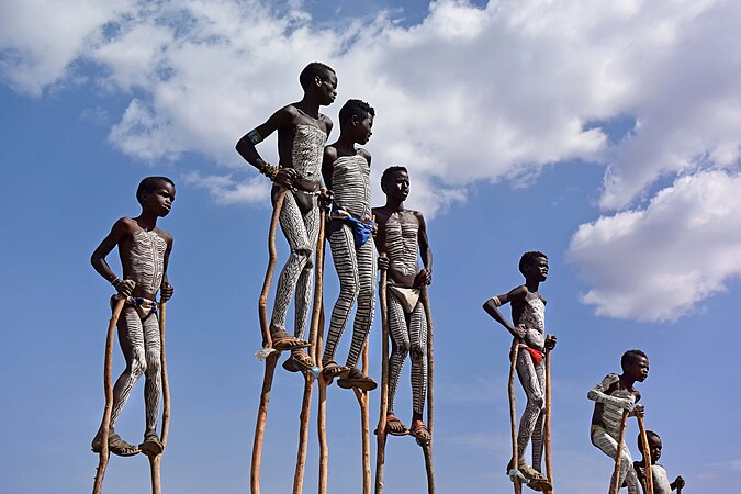 图为埃塞俄比亚的班纳族孩童，身上画有传统的彩绘，站在木制的高跷上。