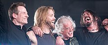 John Paul Jones, Taylor Hawkins, Jimmy Page, and Dave Grohl hugging and smiling onstage