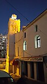 Night shot of mosque with square minaret in a golden spotlight
