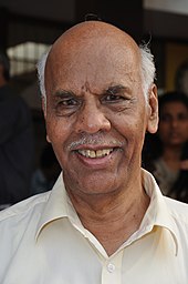 Photograph of an old man in white shirt.