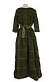 A moss-green pleated linen evening dress with three-quarter length sleeves and a round high neckline. Designed by Sybil Connolly.