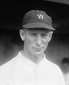 A wearing a white baseball jersey with a dark cap with a white "W" on the center.