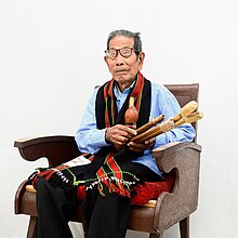Darlong holding the traditional musical instrument 'Rosem'