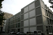 Large grey building, with cars parked outside