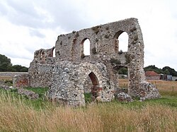 Ruins of a stone building with numerous arches in a rural location