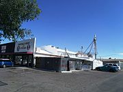 This is the original building of Pratt’s Feed and Supply. Emerson Wilcken Pratt (1901–2001) worked here when it was known as the "Farmers Cooperative". Pratt's brought the business and in 1953 established Pratt’s Feed and Supply. The structure is located at Glendale and 52 Aves. In the background is a mill which Emerson Wilcken Pratt had built to mix different feeds. The building is now used for other business ventures. The property is listed in the Glendale Historic Building Survey, City of Glendale, 1980.