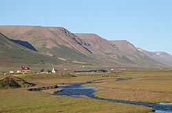 Town of Hof, with the river Hofsá in the foreground and mountains in the background