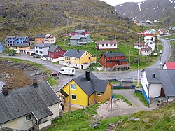 Centre of village, taken from near the Kamøyfjord light. On the right, the Fv172 road comes from the south and proceeds through the centre before heading south again on the left of the picture. The two blue-painted houses on the left hand side of the picture are part of the group of houses which make up the Arran guesthouse. The top floor of the yellow house in the bottom centre of the picture contains the Gallery East of the Sun.