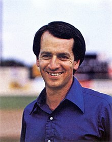 A portrait of a smiling man on a baseball field