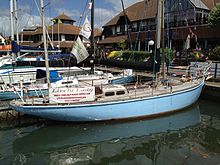yacht with blue hull and light-coloured deck moored in a marina with other boats and buildings beyond