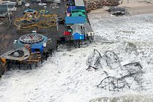 A roller coaster sitting in the ocean; a damaged pier