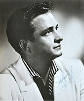 A dark-haired man wearing a light-coloured jacket