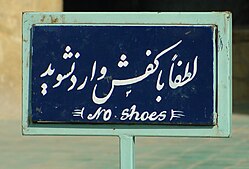 Sign in Persian and English, instructing people to remove their shoes