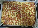 Sheet pan with sliced plums on top of the cake batter