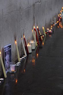 A selection of lit candles arranged along a grey stone wall