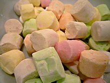 A pile of small cylindrical pieces of confectionery each one a different pale pastel colour