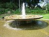 Fountain with three sandstone figures, representing Earth, Water and Fire, flanked on the right hand side by a font, covered with ceramic tiles formed in pre-cast concrete