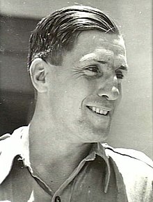 Black and white headshot of a man wearing an open-collared shirt