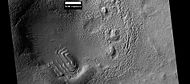 撞击坑中的层状结构，可能曾是覆盖面积更大的层状单元残剩部分，其构成物为从天空落下的冰核尘埃。该照片是高分辨率成像科学设备按照 HiWish 计划拍摄于希腊区。