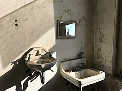 Two sinks in a Tuberculosis ward with the Statue of Liberty reflected in the mirror[85]