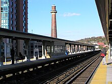 Long train platform, with a brown smokestack in the background