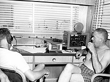 This is a photo of Dr. Walter F. Mazzone and Dr. George Bond inside the communications center of SEALAB I