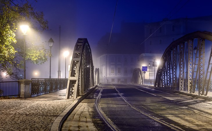 图为位于波兰弗罗茨瓦夫奥得河上的磨坊桥（波兰语：Mosty Młyńskie）（建于1885年）北端，于破晓时分前拍摄。桥上有2条电车（波兰语：Tramwaje we Wrocławiu）轨道。