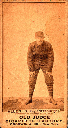 An unclear baseball card image of a mustachioed man in a dark baseball uniform and matching cap crouching with his hands on his knees