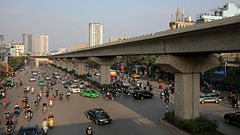 The Metro Line 2 extends as a bridge above a plaza with many people.