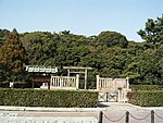 Torii gate and trees behind a stone fence.