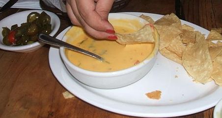 A bowl of chile con queso served with tortilla chips as an appetizer in a Tex-Mex restaurant