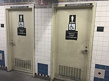 A pair of somewhat decrepit looking metal doors, one labled "MEN", the other labeled "WOMEN", with matching pictograms. Each has a sign saying "Restroom Closed 12 midnight – 5 am" and a wheelchair pictogram.