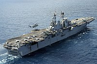 A CH-53E Super Stallion lifting pallets off USS Bataan