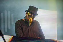A color photograph of German producer Claptone wearing a masquerade mask while performing.