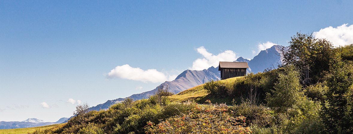 图为从瑞士苏尔库奥姆村望向山谷南边山上白云和库奥姆苏拉旅馆的景观。