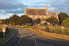 A church with round clerestory windows and a bellcote at the junction of the nave and chancel