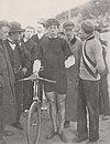 A male cyclist standing next to his bike in a crowd