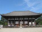 Wooden building with white walls and a trapezoidal roof.