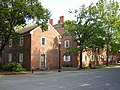 A two-story and a three-story red brick house by a street