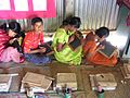 Children sitting on mats, writing on small blackboards, in a classroom in the countryside of Bangladesh, by Mark Knobil