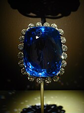 The Logan Sapphire brooch on a display stand