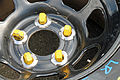Five yellow lug nuts for use on a car with wheels studs